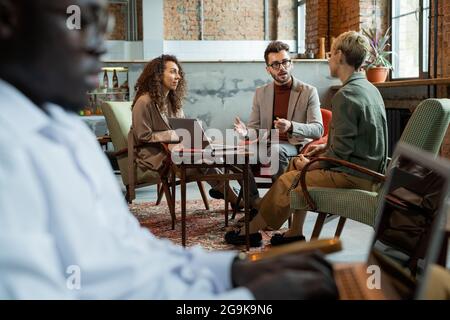 Three managers discussing their ideas by table in modern office or cafe Stock Photo