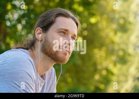 Young handsome bearded man in earphones resting after morning sport training Stock Photo