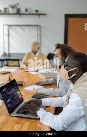 Row of young intercultural co-workers analyzing data and planning work Stock Photo