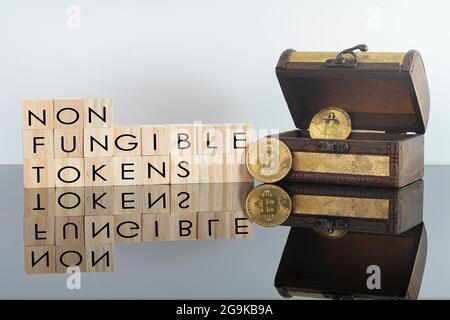 Digital currency concept. Non fungible tokens text on wooden blocks with bitcoins and chest Stock Photo