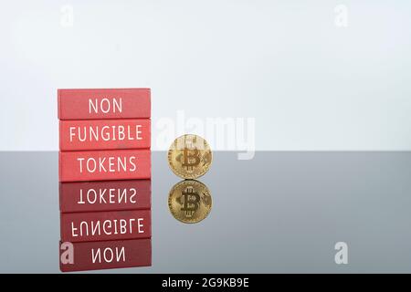 Digital currency concept. Non fungible tokens text on red wooden blocks with bitcoin Stock Photo