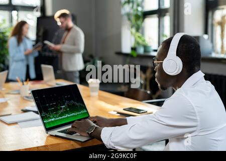 African male economist in headphones using laptop in working environment Stock Photo