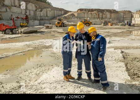 Three builders in workwear discussing sketch of building in tablet Stock Photo