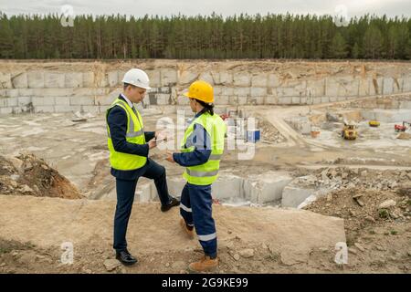 Young foreman and female engineer interacting at construction site Stock Photo
