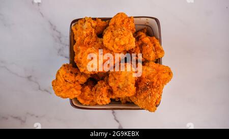 Spicy deep fried chicken tenders strips crunchy in bowl isolated on marble background. Stock Photo