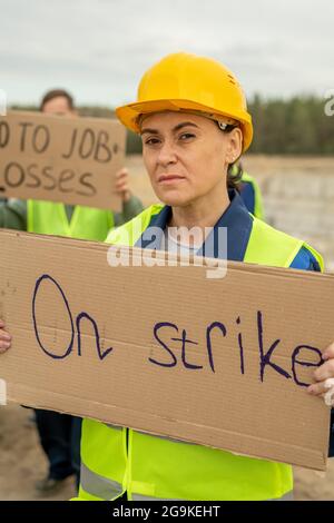 Mature female builder with placards looking at camera on strike Stock Photo