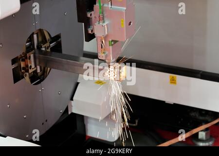 Steel square tube cutting by CNC laser cutting machine. Selective focus. Stock Photo