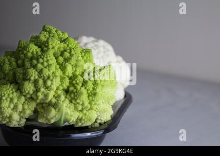 cauliflower and cauliflower romanesco on a black plate. Grey background Stock Photo
