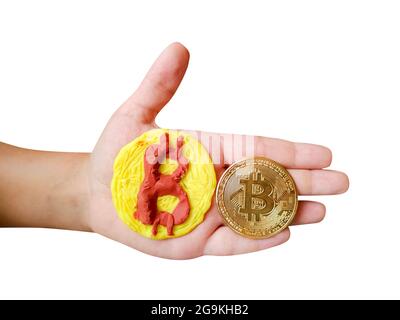 Plasticine and real Bitcoin token coin in kid's hand isolated on white background Stock Photo