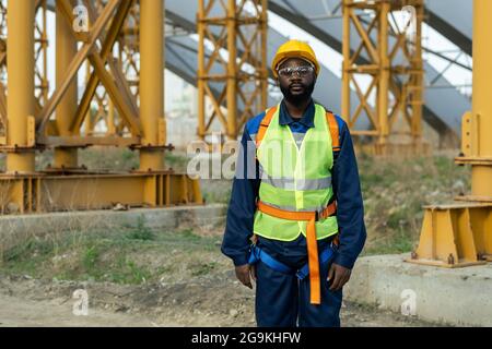 Portrait of African construction worker in equipment looking at camera while standing on construction site Stock Photo