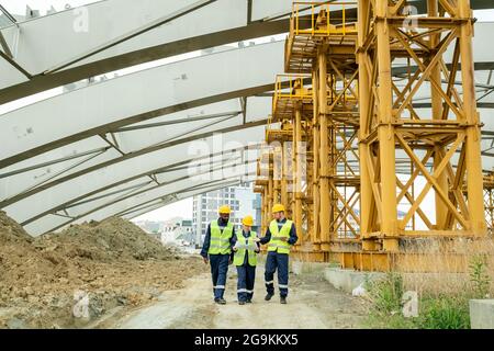 Group of engineers examining blueprint and using digital tablet while working through the construction site, they controlling the construction Stock Photo