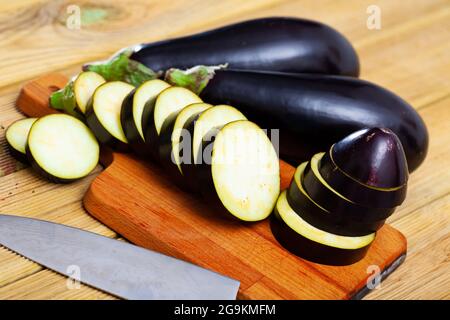 Chopped organic eggplants on wooden background. Vegetarian food concept Stock Photo