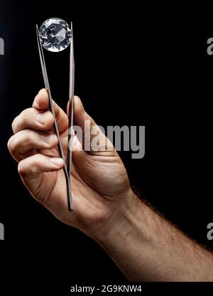 Large gemstone in jeweler's hand close up. Gem identifying and evaluating process. Stock Photo