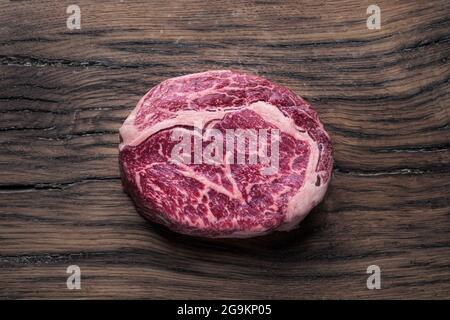 Raw steak ribeye on wooden table. Close-up. Stock Photo