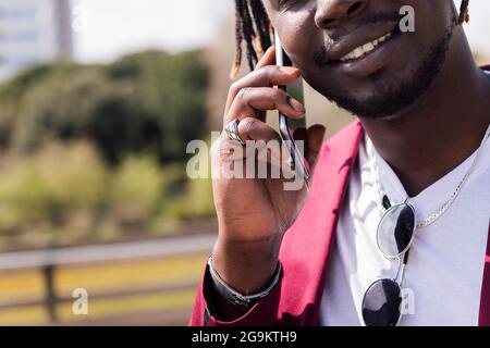unrecognizable black businessman talking on a smart phone outdoors, concept of technology and communication, copy space for text Stock Photo