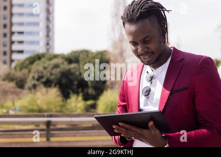 african businessman using a tablet outdoors in the city, technology and remote work concept, copy space for text Stock Photo