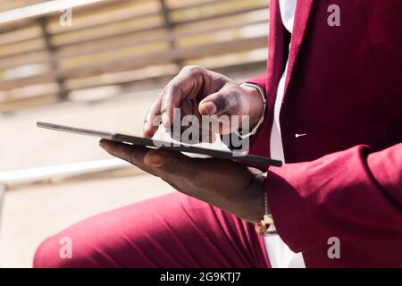 detail of the hands of a black man using a tablet outdoors in the city, technology and remote work concept Stock Photo