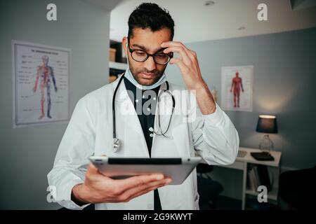 Mixed race male nurse anxious for busy day ahead holding digital tablet Stock Photo