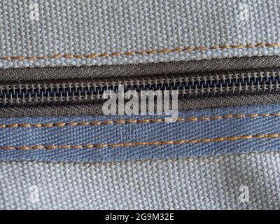 A zipper, zip, fly, or zip fastener, known as a clasp locker, is a commonly used device for binding the edges of an opening of fabric. Close-up. Stock Photo