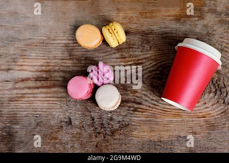 red paper cup with coffee and macaroons on a wooden background. Coffee to go with cakes with copy space Stock Photo