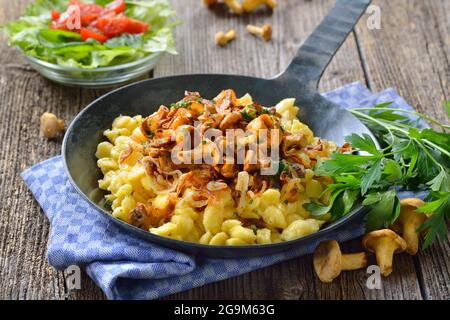 Vegetarian German spaetzle with fried chanterelles and onions served in a frying pan Stock Photo