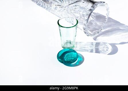 Glass vessels of various shapes and colors. Shadows and reflections. Vase. Tequila glass. Turquoise glass circle. Stock Photo
