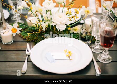 Fresh flowers placed amidst various dishes and beverages on table near people during banquet Stock Photo