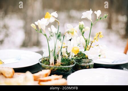 Fresh flowers placed amidst various dishes and beverages on table near people during banquet Stock Photo