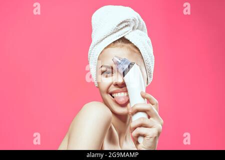 woman with towel on head cleaning face skin care pink background Stock Photo