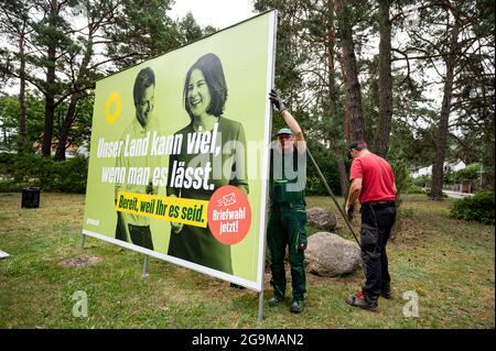 Michendorf, Germany. 26th July, 2021. Workers put up a large-scale poster of the Green Party candidate for chancellor Annalena Baerbock. With this, the Greens set the starting signal for the state-wide billposting for the Bundestag election. The Green Party leader is running as a direct candidate in constituency 61 Potsdam - Potsdam-Mittelmark II - Teltow-Fläming II against the SPD candidate for chancellor Scholz, among others. Credit: Fabian Sommer/dpa/Alamy Live News Stock Photo
