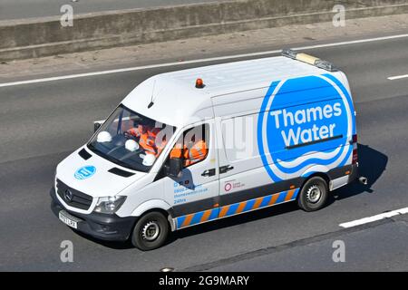 Thames Water logo & team of workers wear hard hats & workmen's high visibility safety jackets driving to work inside Mercedes van on M25 motorway UK Stock Photo