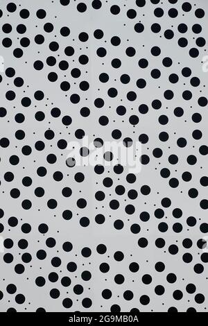 Abstract close up of dotty white background of building cladding panel regular size small circular black round dots & random tiny specks England UK Stock Photo