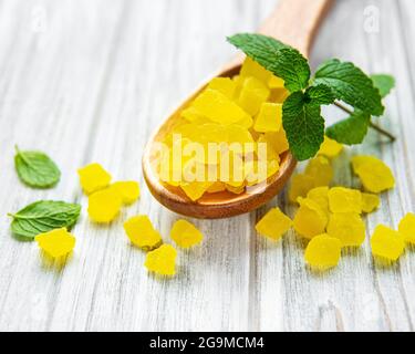 Sweet pineapple succade cubes on white wooden background Stock Photo