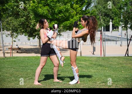 Two people practicing muay thai, boxing, kickboxing, in a park. Sport outdoors. Stock Photo