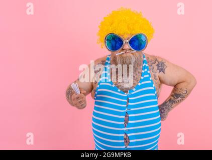 Fat angry man with beard and wig smokes cigarettes Stock Photo