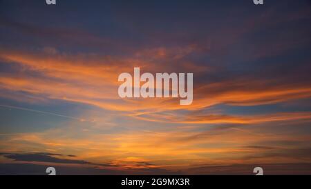 natural background of the sun setting behind a cloud and with sunbeams Stock Photo