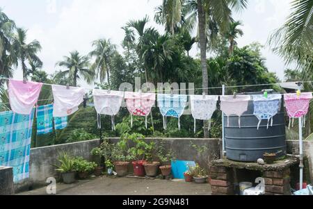 Baby clothes on the roof hang up in Sunlight. Clothes hung on clothesline for drying on terrace of residential house. Kolkata India July 21, 2021 Stock Photo