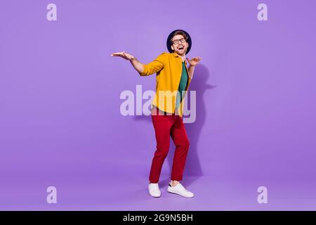 Full length photo of funny funky happy man dance look empty space wear hat isolated on purple color background Stock Photo