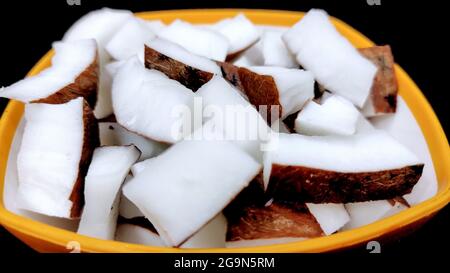 Fresh coconut pieces in a bowl on dark color background with copy space Stock Photo