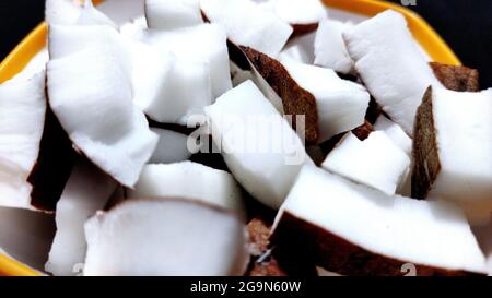 Fresh coconut pieces in a bowl on dark color background with copy space Stock Photo