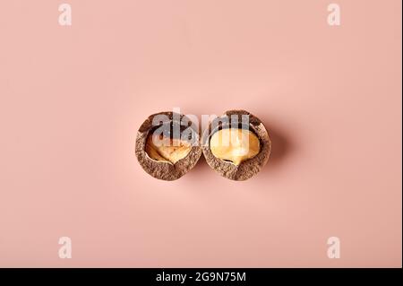 Split macadamia nut on a pink powdery background. Top view, copy space Stock Photo