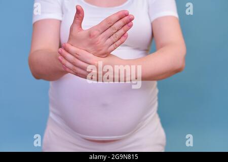 A pregnant woman holds her hand. Tunnel syndrome in the wrist during pregnancy. Stock Photo