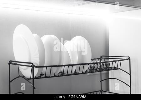 Set of white dishes on the rack in modern kitchen interior background photo Stock Photo