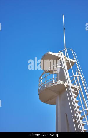 detail of a white concrete watchtower with metal railings on a blue background Stock Photo