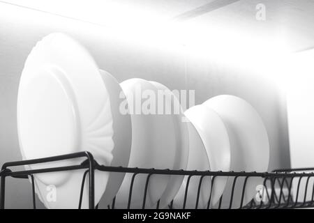 The white plates are flat stacked on the dryer in the kitchen modern interior background Stock Photo
