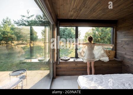 Woman wakes up at country house in nature Stock Photo