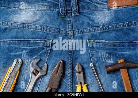 Top view design concept of Labor Day with working tools on blue jeans background. Stock Photo