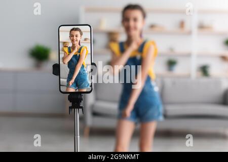 Cheerful teen girl dancing at camera filming video om cellphone Stock Photo