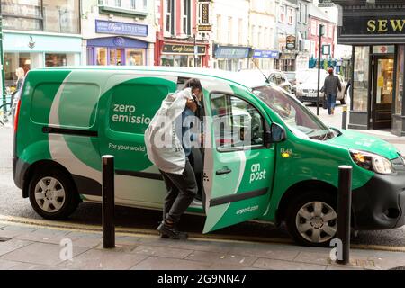 Young An Post or Irish Post employee postman with company branded van collecting letters from street post box in Killarney, County Kerry, Ireland. Occupations concept. Stock Photo