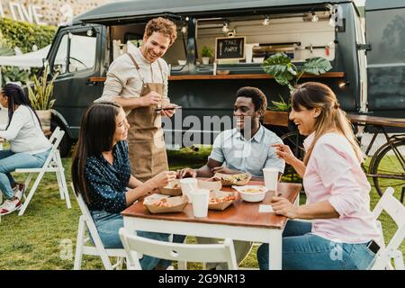 Friendly waiter taking order from diverse friends near food truck Stock Photo